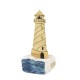 A brass lighthouse on raw marble with painted waves 20x8x8cm.