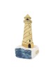 A brass lighthouse on raw marble with painted waves 20x8x8cm.